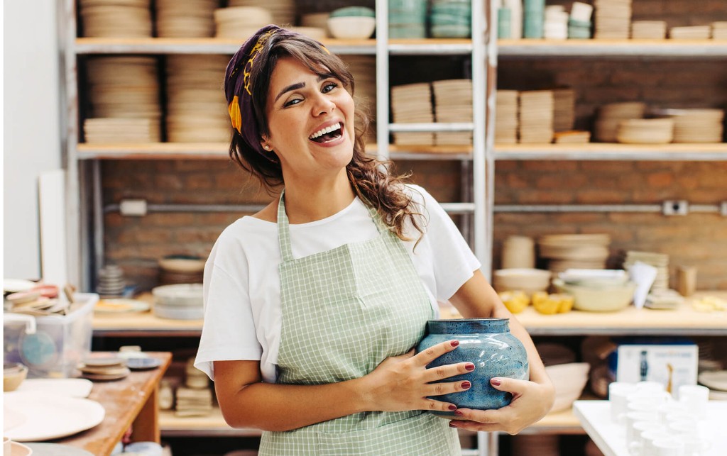 Entrepreneure dans son atelier de céramique tenant un vase fait main
